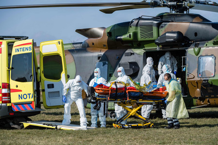 ２日、ドイツ中部ノルトハウゼン近郊の空港で、新型コロナウイルスに感染したフランスの患者を運ぶ医療従事者（ＡＦＰ時事）