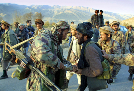 アフガニスタン北部ハナバードの前線で、投降したばかりのタリバン兵（右）からロケット・ランチャーを取り上げる北部同盟の兵士＝２００１年１１月（ＡＦＰ時事）