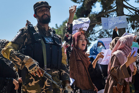 イスラム主義組織タリバン兵の横で、デモを行うアフガニスタンの女性たち＝９月７日、カブール（ＡＦＰ時事）