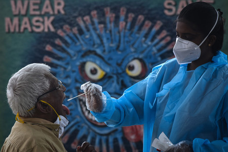 ３日、インド南部チェンナイの駅で、新型コロナウイルスの「オミクロン株」が見つかった南部カルナタカ州からの到着客の検査を行う保健当局者（ＥＰＡ時事）