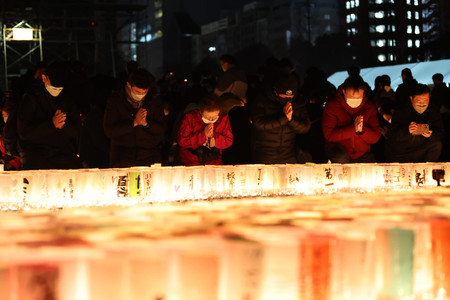 阪神大震災から２７年を迎え、発生時刻に黙とうする人たち＝１７日午前５時４６分、神戸市中央区の東遊園地