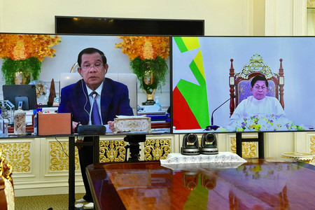 ２６日、カンボジアの首都プノンペン郊外のタクマウで、オンライン会談に臨むフン・セン首相（左）とミャンマー国軍のミンアウンフライン総司令官＝カンボジア政府提供（ＡＦＰ時事）