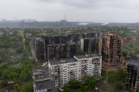 １８日、ウクライナ南東部マリウポリの破壊された住宅（手前）とアゾフスタル製鉄所（奥）（ＡＦＰ時事）