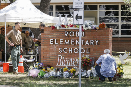 ２５日、米南部テキサス州ユバルディの小学校で、銃撃事件の犠牲者を追悼するため次々置かれる花束（ＥＰＡ時事）