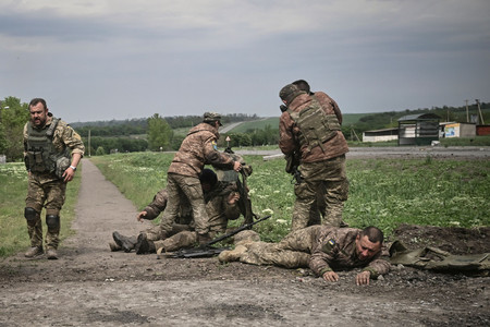 ウクライナ東部ドンバス地方の前線近くで、仲間を助けるウクライナ軍兵士＝２１日（ＡＦＰ時事）