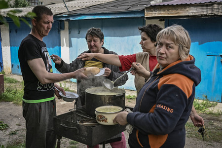 電気や水が止まり、屋外で食事の準備をするウクライナ東部の住民たち＝２６日、リシチャンシク（ＡＦＰ時事）