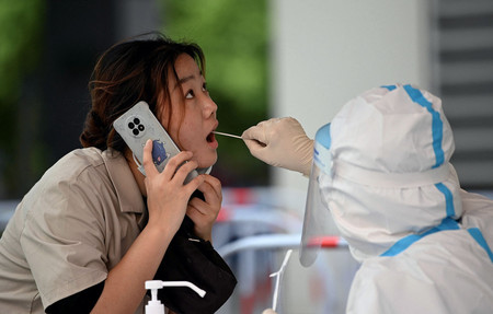 新型コロナウイルス検査場で検体を採取される女性＝２５日、北京（ＡＦＰ時事）