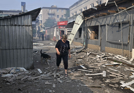 ３日、ウクライナ東部スラビャンスクで、破壊された商店街を歩く女性（ＡＦＰ時事）