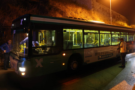 １４日、エルサレム旧市街のユダヤ教聖地付近で、銃撃されたバスを調べるイスラエルの捜査員ら（ＡＦＰ時事）