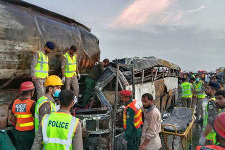 １６日、パキスタン東部パンジャブ州で、タンクローリーにバスが衝突し、炎上した事故現場を捜索する救助隊員ら（ＡＦＰ時事）
