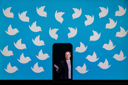 米実業家イーロン・マスク氏を映したスマートフォンを囲む米ツイッターのロゴ（ＡＦＰ時事）