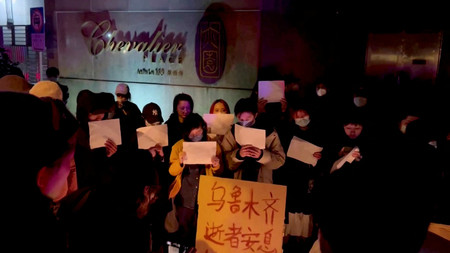 ２６日、上海で、新疆ウイグル自治区ウルムチ市で起きた火災の犠牲者を追悼する人々＝ソーシャルメディアの映像より（ロイター時事）
