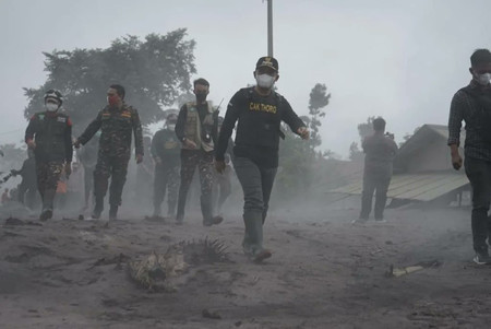 ４日、インドネシア・東ジャワ州のスメル山が噴火し、灰が降り積もった村の中を歩く人々＝住民のツイッターから