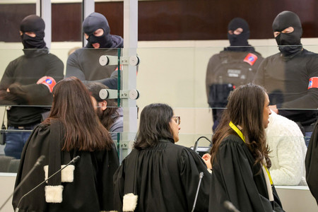 ５日、ブリュッセルの裁判所で、審理開始前に特製ガラスケースに入ったベルギー同時テロの被告と話す弁護士（ＡＦＰ時事）