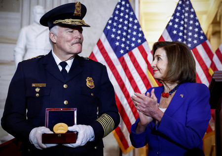 ６日、ワシントンで、ペロシ米下院議長（右）から勲章を受け取る議会警察幹部（ロイター時事）