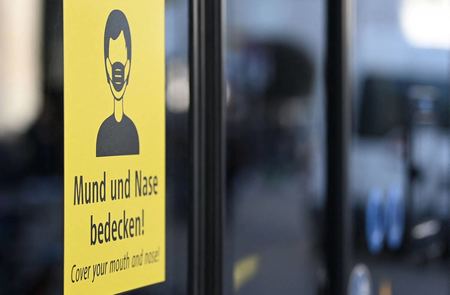 ２０２１年１１月、新型コロナウイルスの感染拡大を受け、バス通勤者にマスク着用を求めるドイツ・ミュンヘン市内の掲示（ＡＦＰ時事）