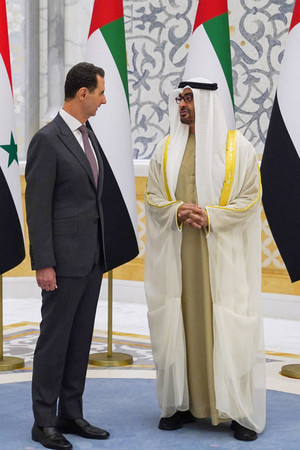 19日、アブダビで、アラブ首長国連邦(UAE)のムハンマド大統領(右)と話すシリアのアサド大統領(AFP時事)