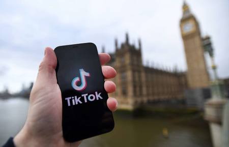 ロンドンの英議会議事堂前で、スマートフォンの画面に表示された「ＴｉｋＴｏｋ（ティックトック）」のロゴ（ＥＰＡ時事）