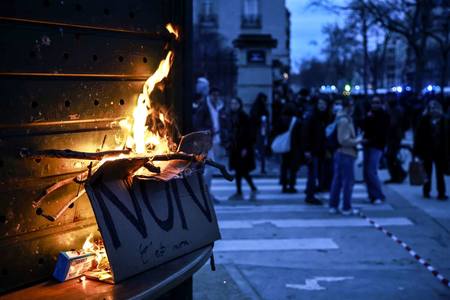 ２０日、パリの広場で行われた年金改革に抗議するデモで燃える、「反対」と書かれたプラカード（ＥＰＡ時事）