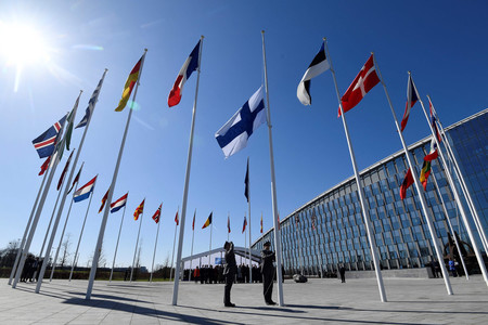 ４日、ブリュッセルの北大西洋条約機構（ＮＡＴＯ）本部で掲揚されるフィンランド国旗（中央）（ＡＦＰ時事）