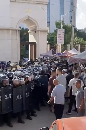 ２７日、中国雲南省のモスク前でにらみ合う警官隊と住民（ツイッターより）