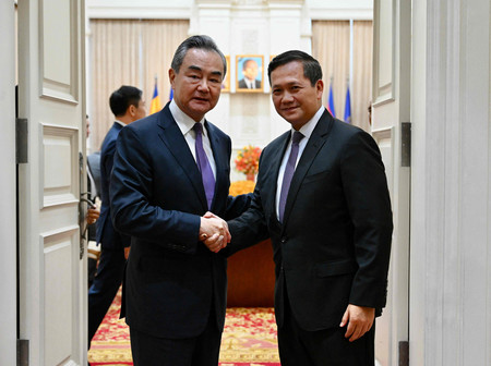 １３日、プノンペンで握手する中国の王毅外相（左）とカンボジア新首相に指名されたフン・マネット氏（カンボジア政府提供）（ＡＦＰ時事）