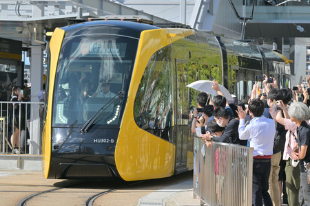 ２６日開業した「宇都宮芳賀ライトレール線」の一番電車と集まった人々＝同日午後、宇都宮市
