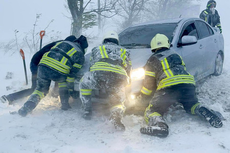 ２７日、ウクライナ南部オデッサ州で、大雪の中、車を押す救助隊員（非常事態庁提供）（ＡＦＰ時事）