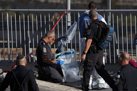 ３０日、エルサレムで起きた乱射事件の現場で、ライフル銃を押収するイスラエルの警察官（ＡＦＰ時事）