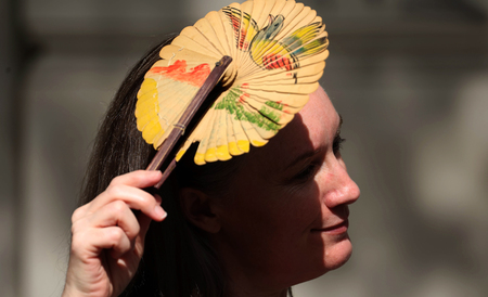 扇子で日差しを遮る女性＝９月５日、ロンドン（ＥＰＡ時事）