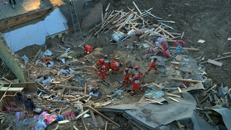 １９日、中国内陸の青海省海東市で、地震によるがれきの中を捜索する救助隊員ら（ＥＰＡ時事）