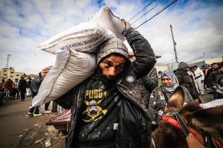 ２８日、パレスチナ自治区ガザ南部ラファで、国連パレスチナ難民救済事業機関（ＵＮＲＷＡ）の拠点で食料を受け取る男性（中央）（ＡＦＰ時事）