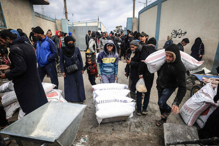 パレスチナ自治区ガザにある国連パレスチナ難民救済事業機関（ＵＮＲＷＡ）の施設で、食料を受け取る住民ら＝１月２８日、南部ラファ（ＡＦＰ時事）