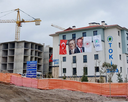 トルコ大地震の被災者向けに建設された公営住宅。建国の父ケマル・アタチュルクとエルドアン大統領の肖像の垂れ幕が下がっている＝１月２９日、トルコ南部カフラマンマラシュ郊外