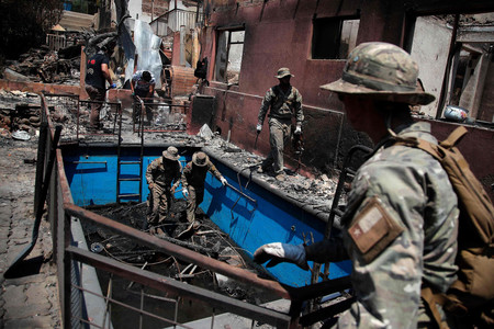 ５日、チリ中部バルパライソ州で、焼失した住居の片付け作業に当たる兵士（ＡＦＰ時事）
