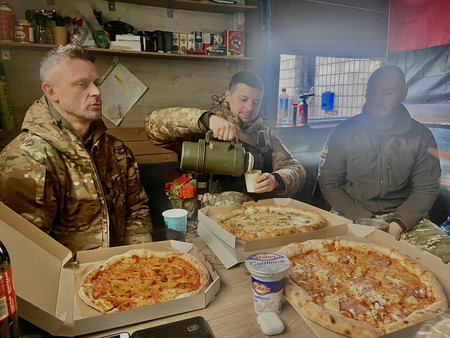 防空拠点でピザを囲むウクライナ最高裁判事のユーリ・チュマクさん（左）ら義勇兵部隊「ムリヤ」のメンバー＝１月２７日、キーウ南郊