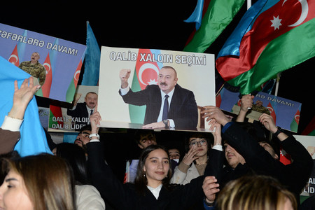７日、アゼルバイジャンの首都バクーで、アリエフ大統領の写真を掲げる支持者ら（ＡＦＰ時事）