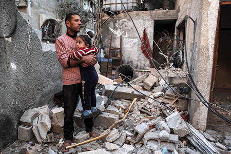 ８日、パレスチナ自治区ガザ南部ラファの破壊された住居で、子供を抱き締める男性（ＡＦＰ時事）