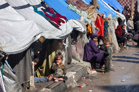 ８日、パレスチナ自治区ガザ南部ラファで、テントの外に座る避難民（ＡＦＰ時事）