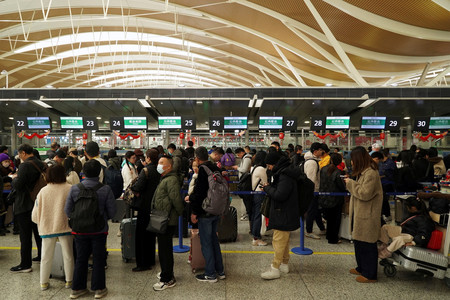 ９日、春節を控え、中国・上海の上海浦東国際空港のカウンターに並ぶ人々（ロイター時事）