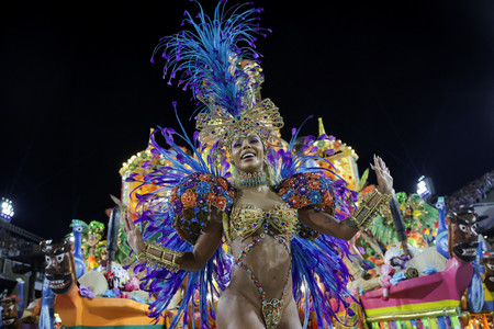 １１日夜、ブラジル・リオデジャネイロの専用競技場で始まった精鋭チームによるカーニバルのサンバパレードで踊りを披露する女性（ロイター時事）