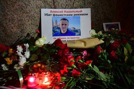 １６日、ロシア北西部サンクトペテルブルクの政治犯の追悼碑に置かれた反体制派指導者ナワリヌイ氏の写真と花々（ＡＦＰ時事）