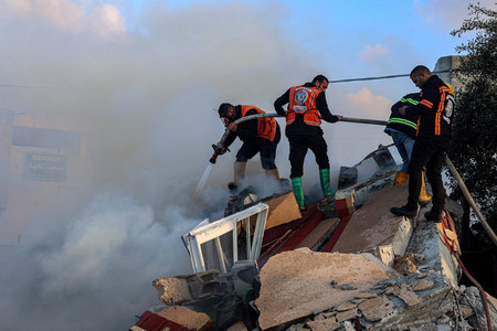 １９日、パレスチナ自治区ガザ南部ラファで、イスラエルの砲撃後に建物の消火に当たる人々（ＡＦＰ時事）