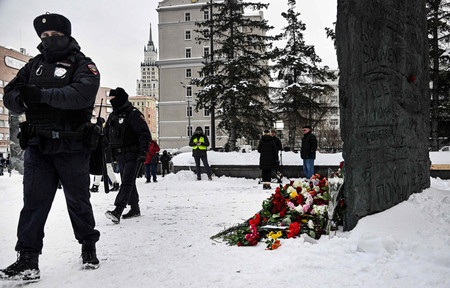 ロシアの反体制派指導者ナワリヌイ氏の獄死を受け、献花された政治犯追悼碑の前に立つ警官＝１７日、モスクワ（ＡＦＰ時事）
