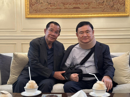 ２１日、バンコクで面会したタイのタクシン元首相（右）とカンボジアのフン・セン前首相（フン・セン氏のフェイスブックより・時事）