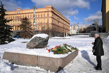 ２０日、モスクワの政治犯追悼碑前で十字を切る男性（ＡＦＰ時事）