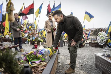 ２３日、ウクライナ西部リビウの墓地で、追悼式典に参加するゼレンスキー大統領（手前）（ＥＰＡ時事）