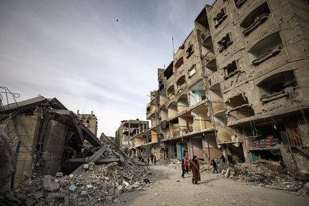 ２３日、パレスチナ自治区ガザ南部で破壊された集合住宅跡を歩く住民ら（ＥＰＡ時事）
