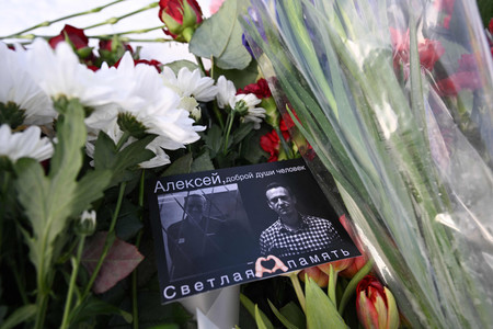 政治犯の追悼碑の花に添えられたナワリヌイ氏の写真付きカード＝２０日、モスクワ（ＡＦＰ時事）