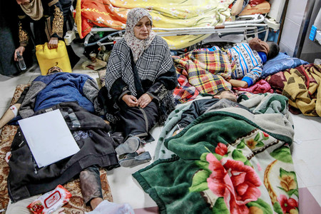 パレスチナ自治区ガザ市のシファ病院でけが人の間に座る女性（中央）＝２月２９日（ＡＦＰ時事）